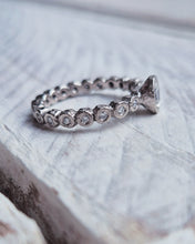 Load image into Gallery viewer, Side view showing the elegant yet organic looking engagement ring which has a bezel set full diamond band with luxurious ocean diamonds set within it.