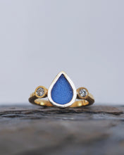 Load image into Gallery viewer, Front view of a ABYSSAL trilogy style engagement ring with a blue waterdrop shaped piece of sea glass in the center bezel with premium quality ocean diamonds either side. Inspired by the oceans raw beauty.