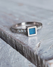 Load image into Gallery viewer, Side view of modern looking pave set diamonds either side of an art deco inspired square shaped piece of sea glass. This is our ELYSIUM engagement ring.