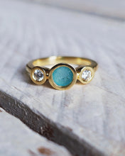 Load image into Gallery viewer, Close-up of a bespoke CAVERN engagement ring showing turquoise sea glass with sparkly ocean diamonds either side in 18ct yellow gold.