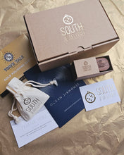 Load image into Gallery viewer, A close up of South Jewellery's luxurious and eco-friendly packaging. Featuring a branded poastal packaging box, handmade walnut ring box, jewellery pouch, business card, thank you card, ocean diamond certificate and talk town polishing cloth.