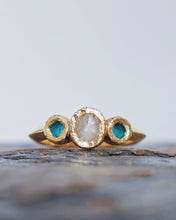 Load image into Gallery viewer, Close-up of a bespoke ROCK engagement ring showcasing an incredible treasure, a diamond found in the ocean and left in its raw shape. Turquoise sea glass sits either side and this jewel has been made in 18ct yellow gold.