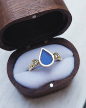 Load image into Gallery viewer, Side view of an 18ct yellow gold ocean-inspired ABYSSAL engagement ring, handcrafted in Cornwall. It has waterdrop blue sea glass in the middle with an ocean diamond either side.