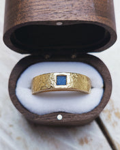Load image into Gallery viewer, A wedding band for men that is handcrafted in 18ct yellow gold and has a piece of sea glass handcarved into a square and flush set within the gold band.