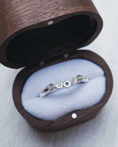 Curved wedding ring that is designed to interlock with an engagement ring. It features bezel set sea glass and diamonds.