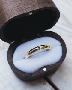 Side view showing the plain wedding ring which is a traditional D shape style. A blueish green piece of sea glass has been set in the 18ct yellow gold band.
