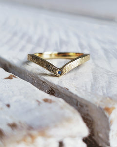 Close up showing flush set blue sea glass in a wishbone style wedding ring that is handmade in 18ct yellow gold.