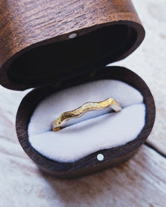 Close up that shows the beautiful curves of a uniquely shaped wave wedding ring that has been handcrafted in 18ct gold.