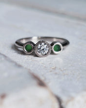 Load image into Gallery viewer, Close-up of a bespoke LEGACY engagement ring showcasing an incredible diamond found in the ocean with hammered textured bezels. Our clients sea glass sits either side of the central diamond and this ring has been made in 18ct white gold.
