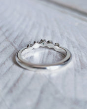 Load image into Gallery viewer, Close up showing the curve of the wedding ring that is designed to flow around the setting of an engagement ring. This design has one piece of sea glass and four diamond in bezel settings.
